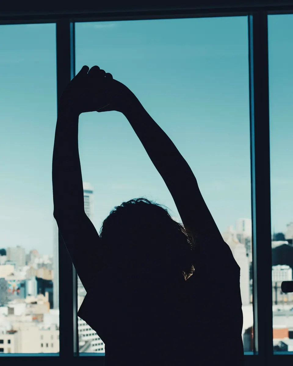 A silhouette stretching in front of a window over the city in the morning